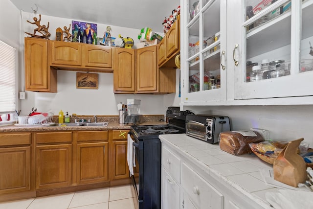 85 N Saint Augustine Blvd Unit 1, Saint Augustine, FL 32080 - kitchen featuring black / electric stove, tile counters, a sink, light tile patterned floors, and glass insert cabinets