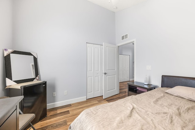 bedroom featuring wood-type flooring, a closet, and a high ceiling