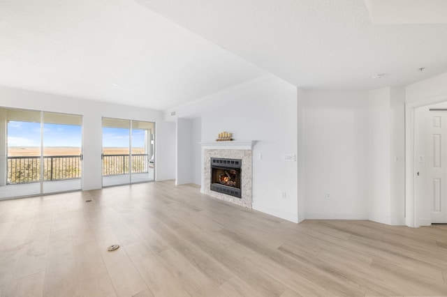 unfurnished living room featuring light hardwood / wood-style flooring, a tile fireplace, and a textured ceiling