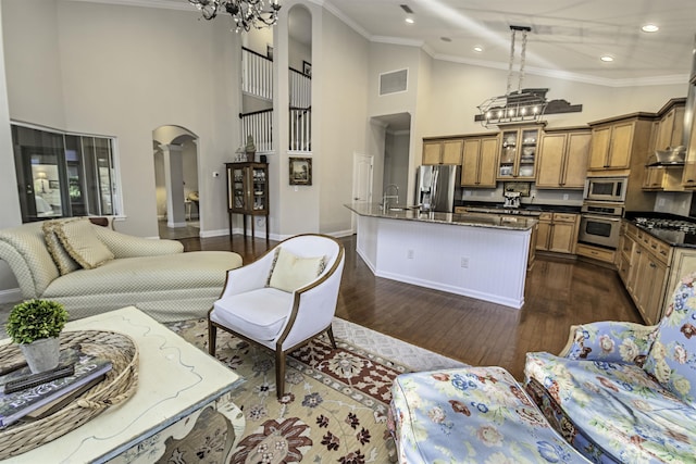 living room with arched walkways, a notable chandelier, dark wood-type flooring, visible vents, and ornamental molding