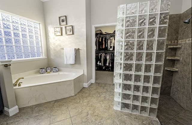 bathroom with tile patterned flooring, a walk in closet, a garden tub, and walk in shower