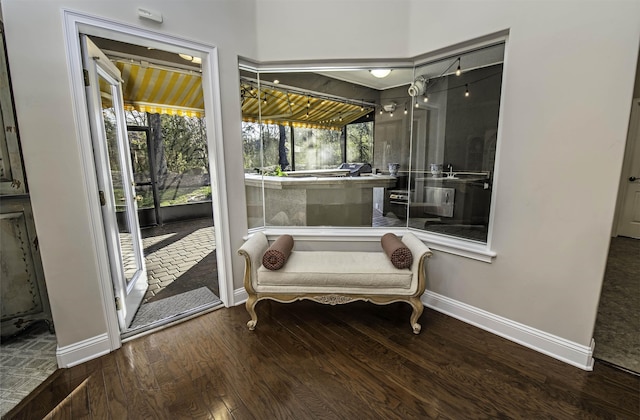 sitting room featuring wood finished floors, a sunroom, and baseboards