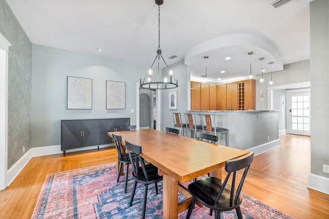 dining space with light wood-type flooring and a notable chandelier