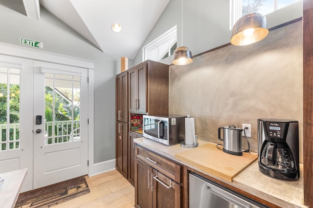 kitchen featuring dark brown cabinetry, stainless steel appliances, vaulted ceiling, pendant lighting, and light hardwood / wood-style floors