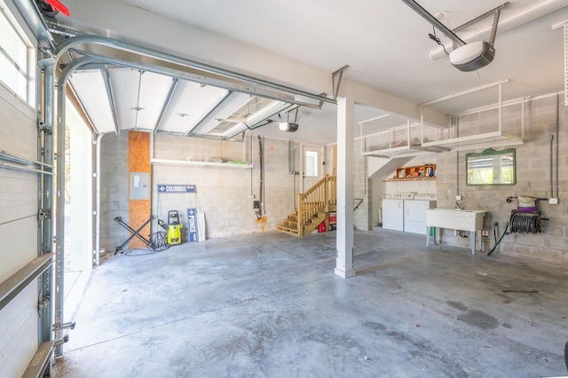 garage with electric panel, sink, a garage door opener, and independent washer and dryer