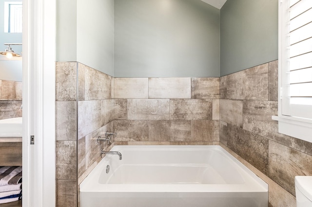 bathroom with a bathtub, tile walls, and toilet