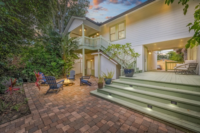 back house at dusk with a patio, a deck, and an outdoor fire pit