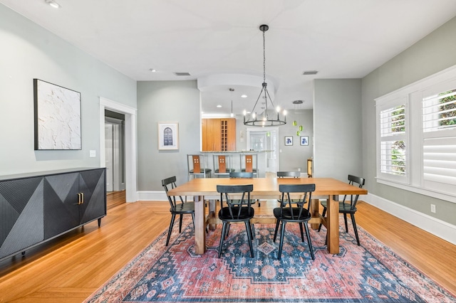 dining area featuring wood-type flooring and an inviting chandelier