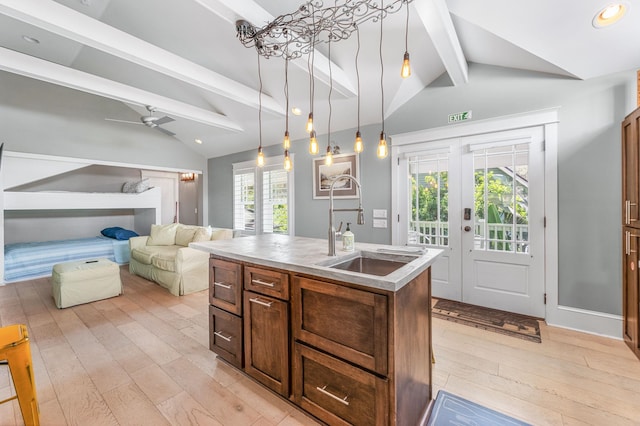 kitchen with vaulted ceiling with beams, light hardwood / wood-style flooring, an island with sink, and hanging light fixtures