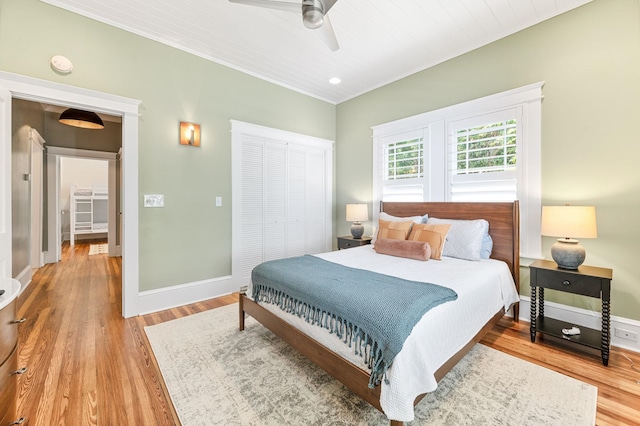 bedroom with ceiling fan, light hardwood / wood-style floors, crown molding, and a closet