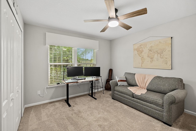 carpeted office space featuring baseboards and a ceiling fan