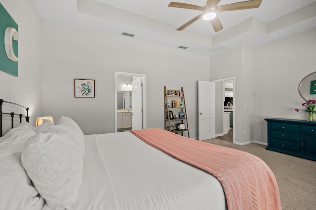 bedroom with connected bathroom, a raised ceiling, a towering ceiling, ceiling fan, and carpet