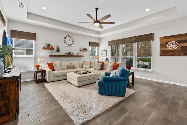 living room with ceiling fan and a tray ceiling