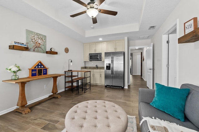 interior space featuring ceiling fan, a raised ceiling, baseboards, and wood tiled floor