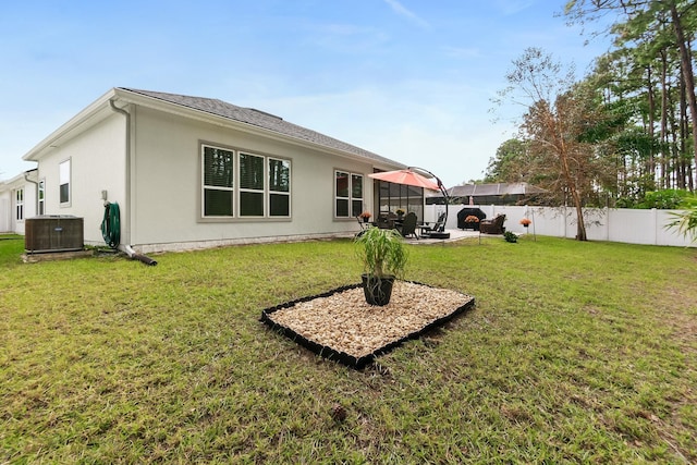 back of property featuring central AC, a lawn, stucco siding, a fenced backyard, and a patio