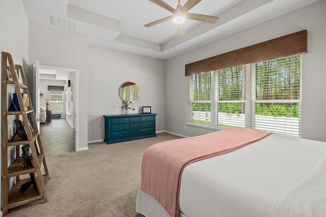 carpeted bedroom featuring ceiling fan and a tray ceiling