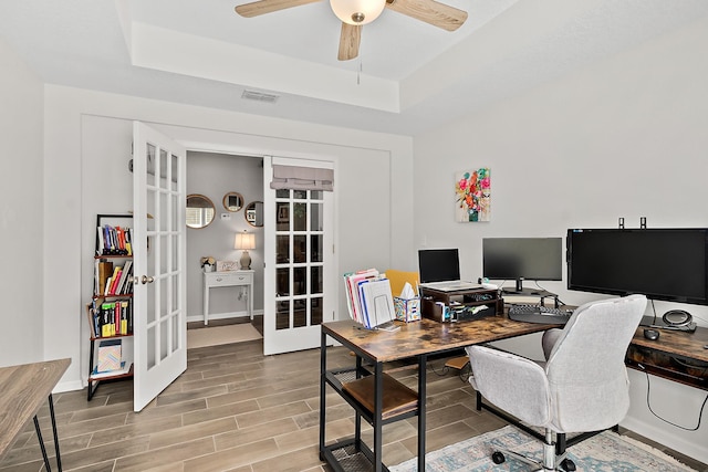 home office featuring visible vents, ceiling fan, wood finish floors, french doors, and a raised ceiling