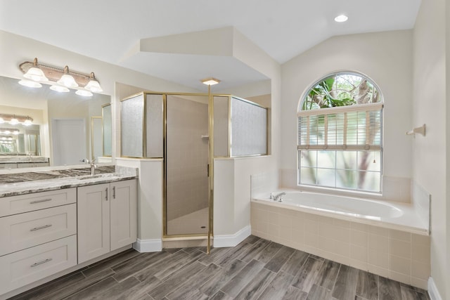 bathroom featuring a shower stall, a garden tub, vanity, wood finished floors, and vaulted ceiling