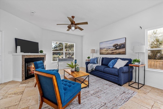 living room with ceiling fan, a healthy amount of sunlight, and a fireplace