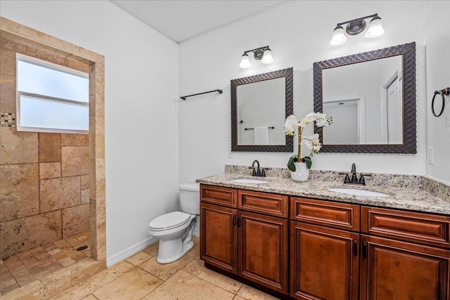 bathroom with a tile shower, vanity, and toilet