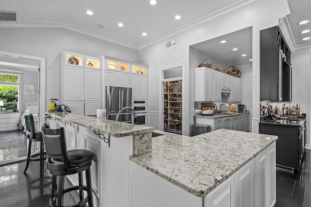 kitchen with light stone countertops, appliances with stainless steel finishes, white cabinetry, and a spacious island