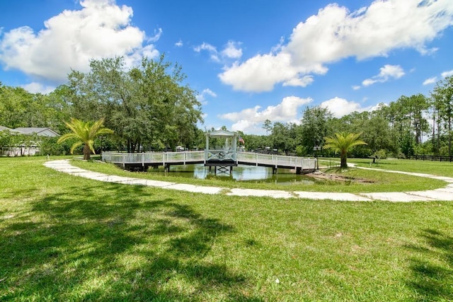 view of community with a lawn, a boat dock, and a water view