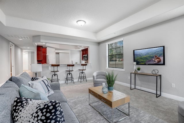 carpeted living room featuring a textured ceiling and a tray ceiling