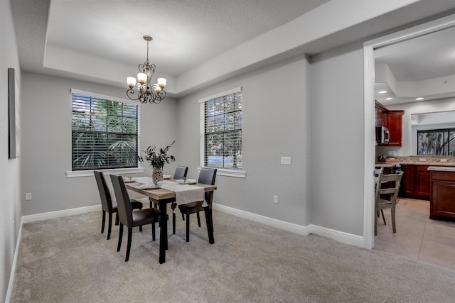 carpeted dining area featuring a raised ceiling and a chandelier