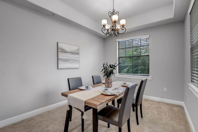 dining room with a tray ceiling, a chandelier, and light carpet