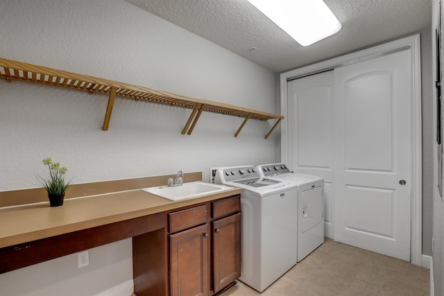 washroom featuring sink, washing machine and dryer, cabinets, and a textured ceiling