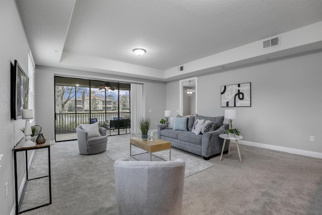 living room with light carpet, a raised ceiling, and a textured ceiling