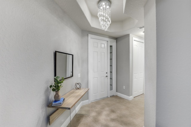 foyer entrance with an inviting chandelier and a tray ceiling