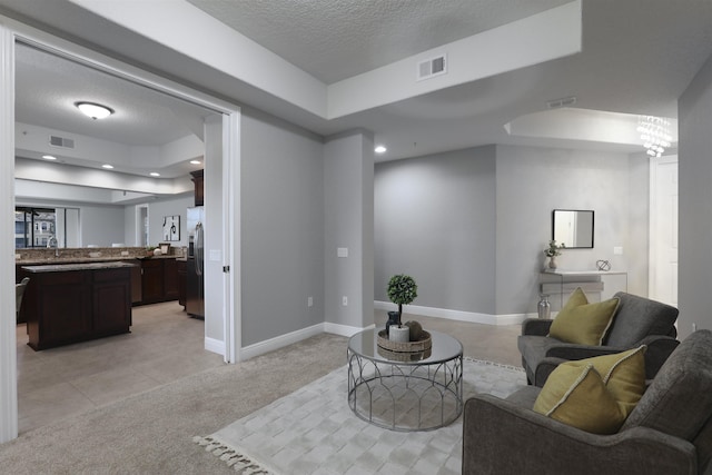 carpeted living room featuring a raised ceiling and a textured ceiling