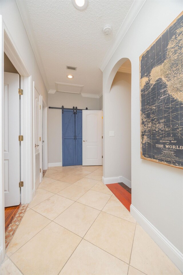 2 Lisbon St, Saint Augustine, FL 32080 - hallway with ornamental molding, tile patterned floors, a textured ceiling, arched walkways, and a barn door