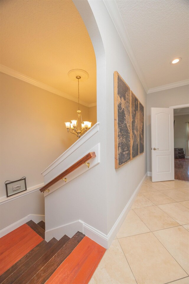 2 Lisbon St, Saint Augustine, FL 32080 - staircase with crown molding, baseboards, a chandelier, tile patterned flooring, and arched walkways