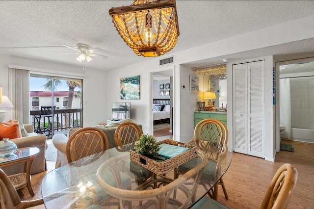 880 A1A Beach Blvd, Saint Augustine Beach, FL 32080 - dining room featuring light wood-style floors, visible vents, ceiling fan with notable chandelier, and a textured ceiling