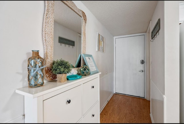 880 A1A Beach Blvd, Saint Augustine Beach, FL 32080 - doorway to outside with light wood-type flooring, wainscoting, and a textured ceiling