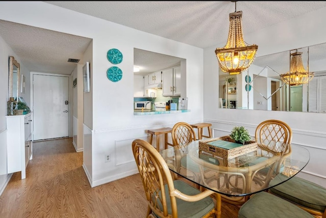880 A1A Beach Blvd, Saint Augustine Beach, FL 32080 - dining space featuring an inviting chandelier, a textured ceiling, visible vents, and wood finished floors