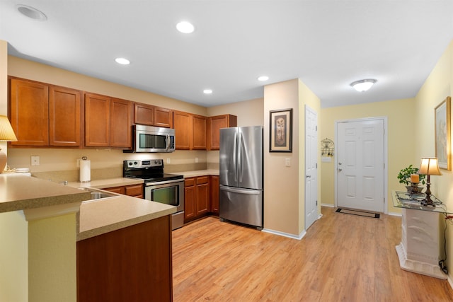 kitchen featuring kitchen peninsula, stainless steel appliances, light hardwood / wood-style flooring, and sink