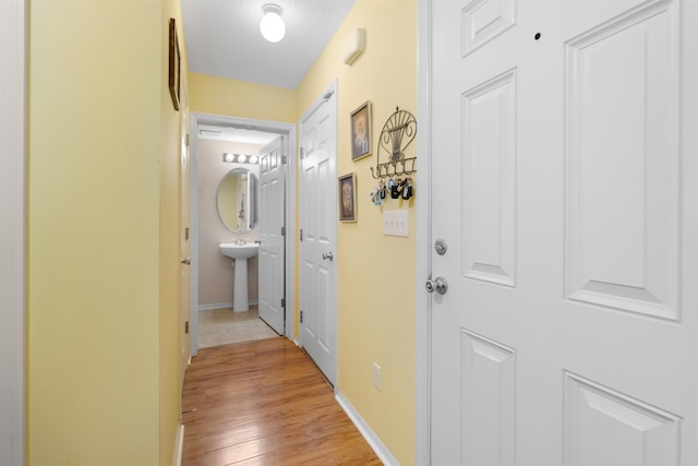 hall featuring a textured ceiling and light hardwood / wood-style flooring