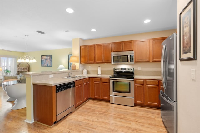 kitchen featuring appliances with stainless steel finishes, decorative light fixtures, light hardwood / wood-style floors, kitchen peninsula, and a chandelier