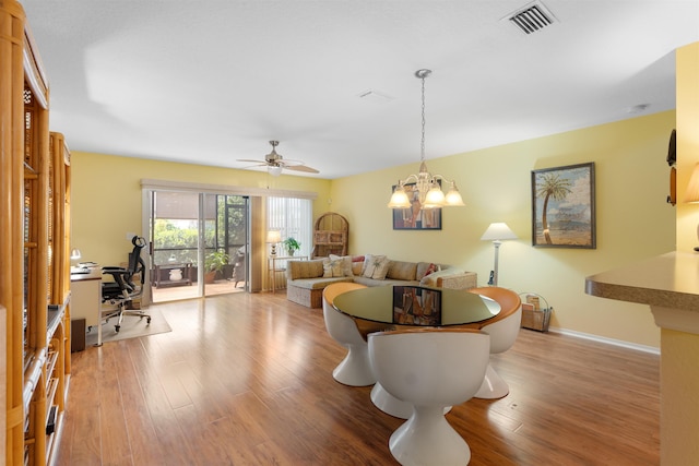 living room with ceiling fan with notable chandelier and light hardwood / wood-style floors