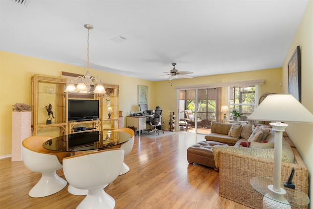 living room with ceiling fan with notable chandelier and light hardwood / wood-style floors