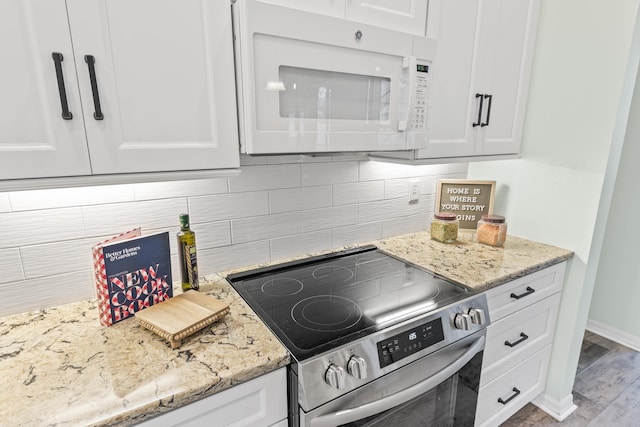 4 Eastgate Ln, Palm Coast, FL 32164 - kitchen with white microwave, stainless steel range with electric cooktop, white cabinets, backsplash, and light stone counters