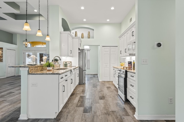 4 Eastgate Ln, Palm Coast, FL 32164 - kitchen with a sink, appliances with stainless steel finishes, dark stone countertops, a towering ceiling, and white cabinetry