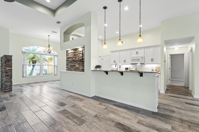 4 Eastgate Ln, Palm Coast, FL 32164 - kitchen with white microwave, a kitchen bar, a high ceiling, wood finished floors, and a peninsula