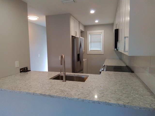 kitchen with range, white cabinetry, sink, kitchen peninsula, and stainless steel fridge