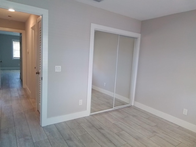 unfurnished bedroom with light hardwood / wood-style flooring and a closet