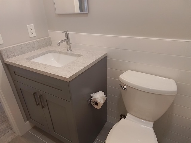 bathroom with toilet, tile walls, and vanity