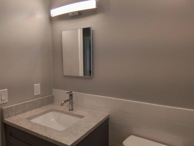 bathroom featuring tile walls, toilet, and vanity